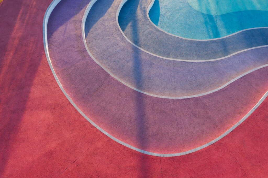 Aerial view of curved, colorful patterns on a stepped surface, featuring shades of red, purple, and blue intertwined with white lines.